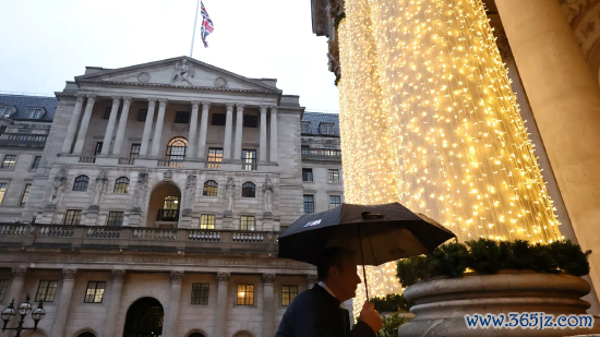2025 年 12 月 18 日英国伦敦，英国央行货币战术委员会降息当日，又名路东说念主撑伞走过英国央行大楼。